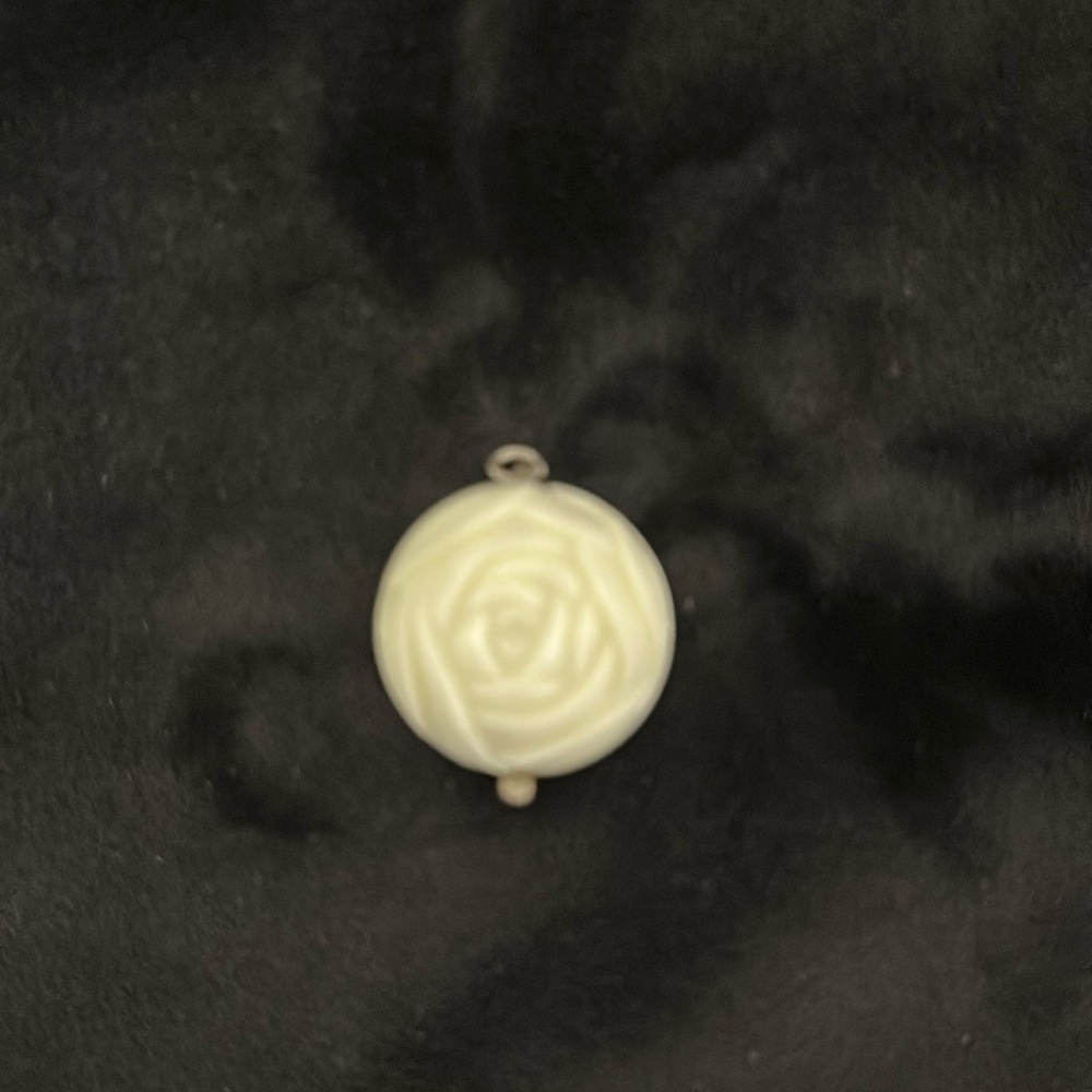 Round white color rose design pendant. Opens and inside is a tiny rosary.